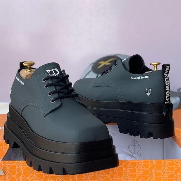 Naked Wolf Loafer in a stylish, black color with a platform sole and thick midsoles. The brand's logo and tagline are prominently displayed on the side. The shoe is shown in a box, ready for purchase.