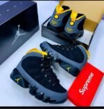 Sneakers in a sleek black and gray colorway with yellow accents, perfect for Nigerian style.