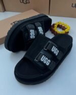 Sneakers, loafers, and slip-ons in black, perfect for any Nigerian wardrobe. Ugg's signature 'UGG' is featured on the straps, adding a touch of personality.