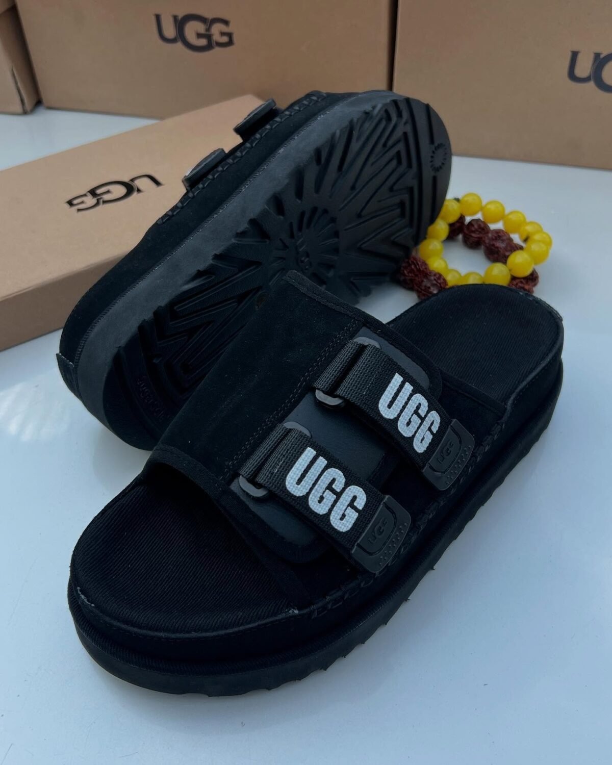 Sneakers, loafers, and slip-ons in black, perfect for any Nigerian wardrobe. Ugg's signature 'UGG' is featured on the straps, adding a touch of personality.